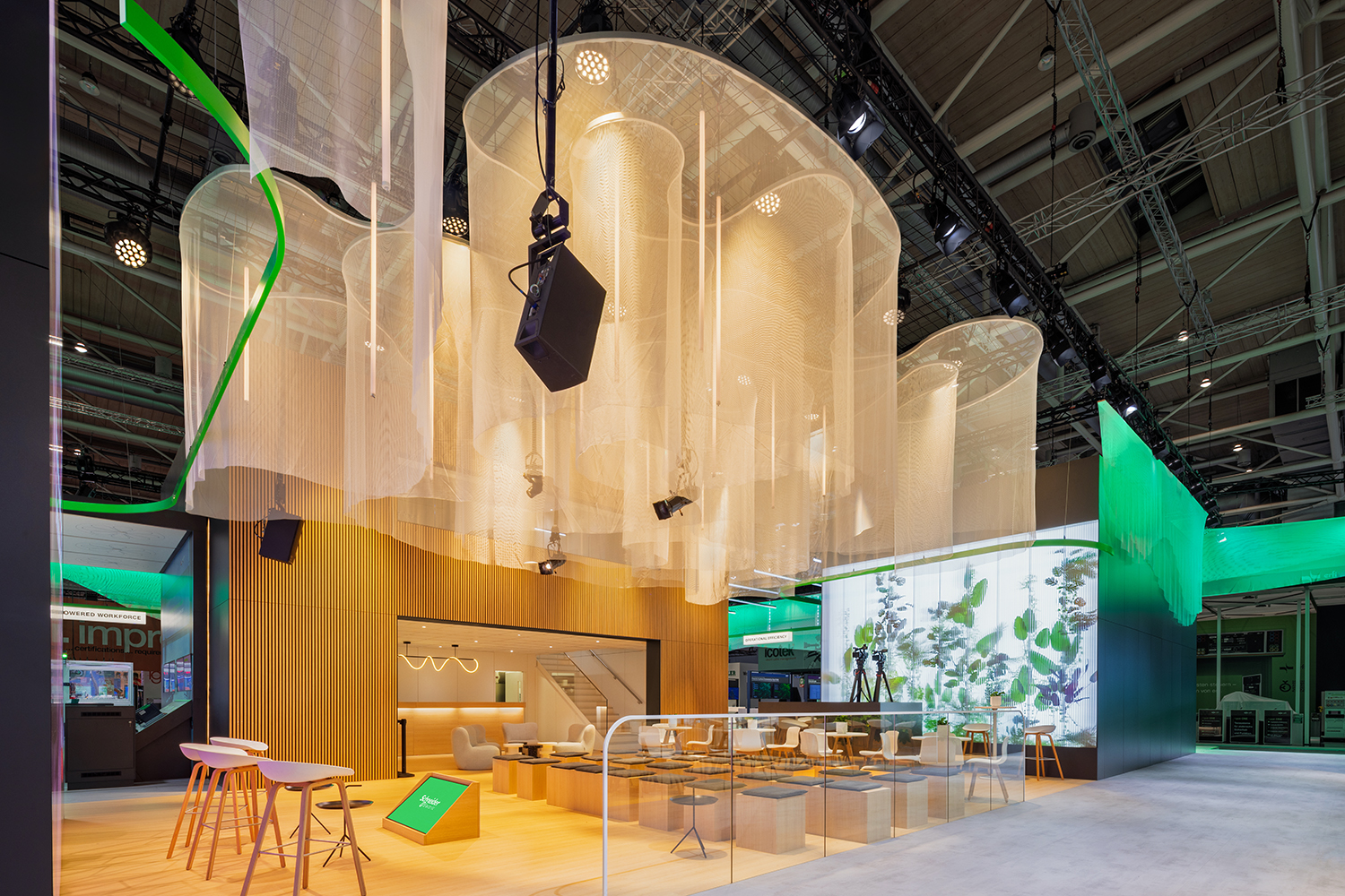 Zentrale Vortrags- und VIP-Lounge von Schneider Electric mit transparenten Hängestoffen, Lichtzylindern und Glasbrüstung.