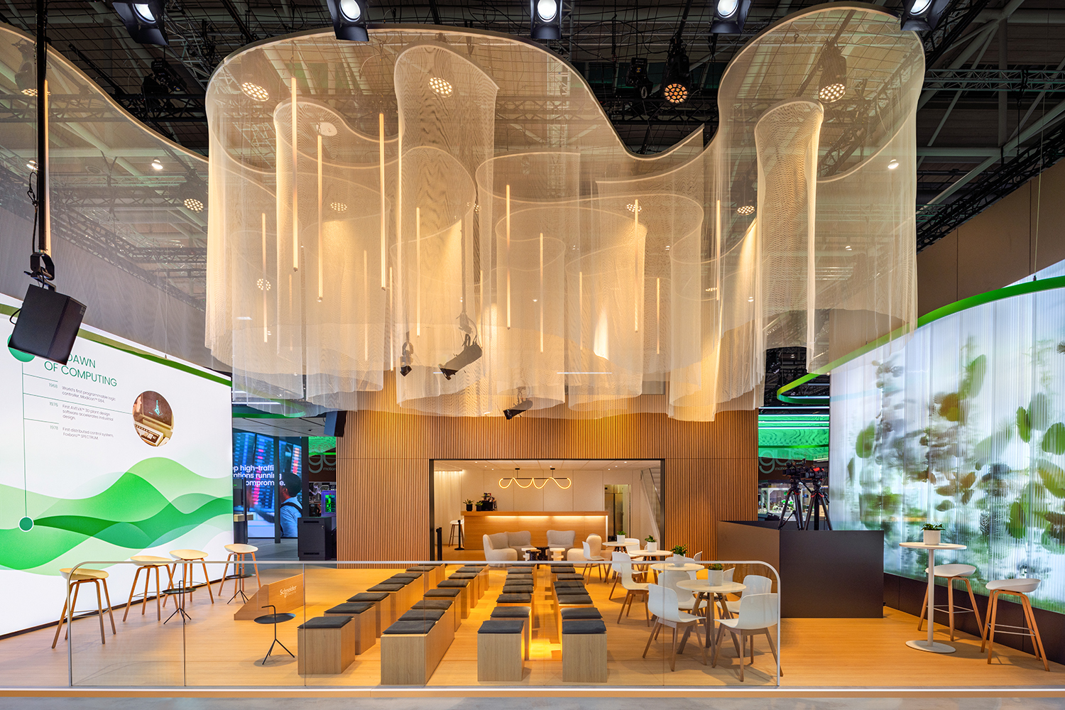 Detailansicht des Auditoriumsbereichs von Schneider Electric auf der HMI 2026 mit organischer Mesh-Deckenlandschaft und Holzlamellenwand.
