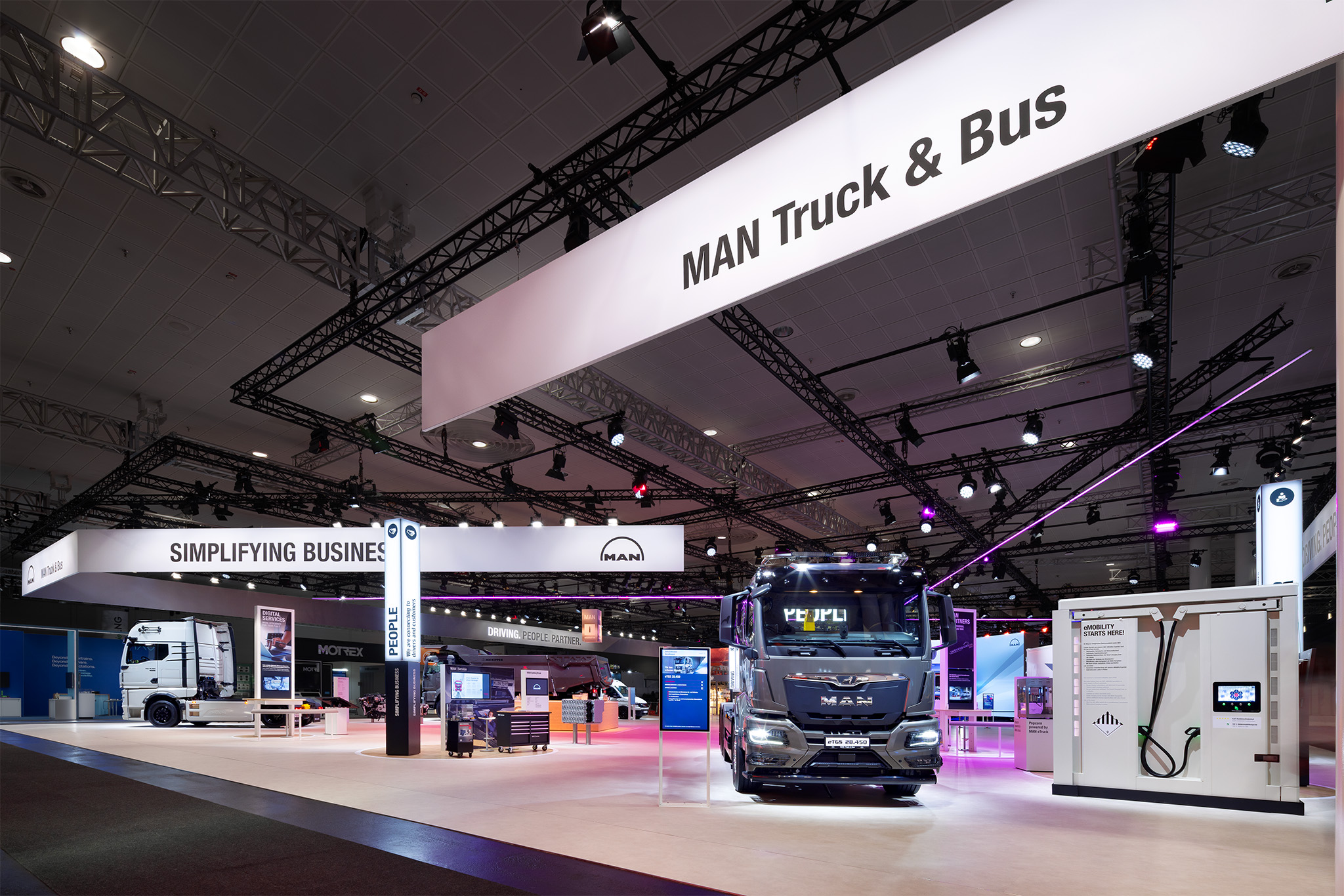 Messestand von MAN Truck & Bus auf der IAA Hannover mit Lkw und Ladesäule.