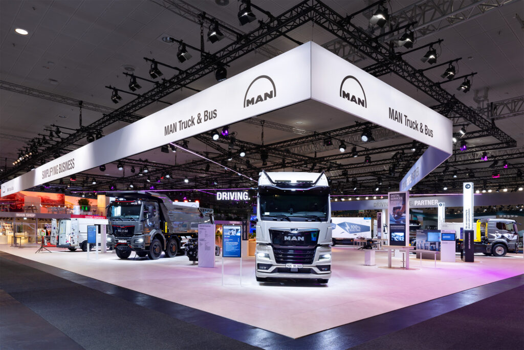Messestand von MAN Truck & Bus auf der IAA Hannover mit Lkw und Ladesäule.