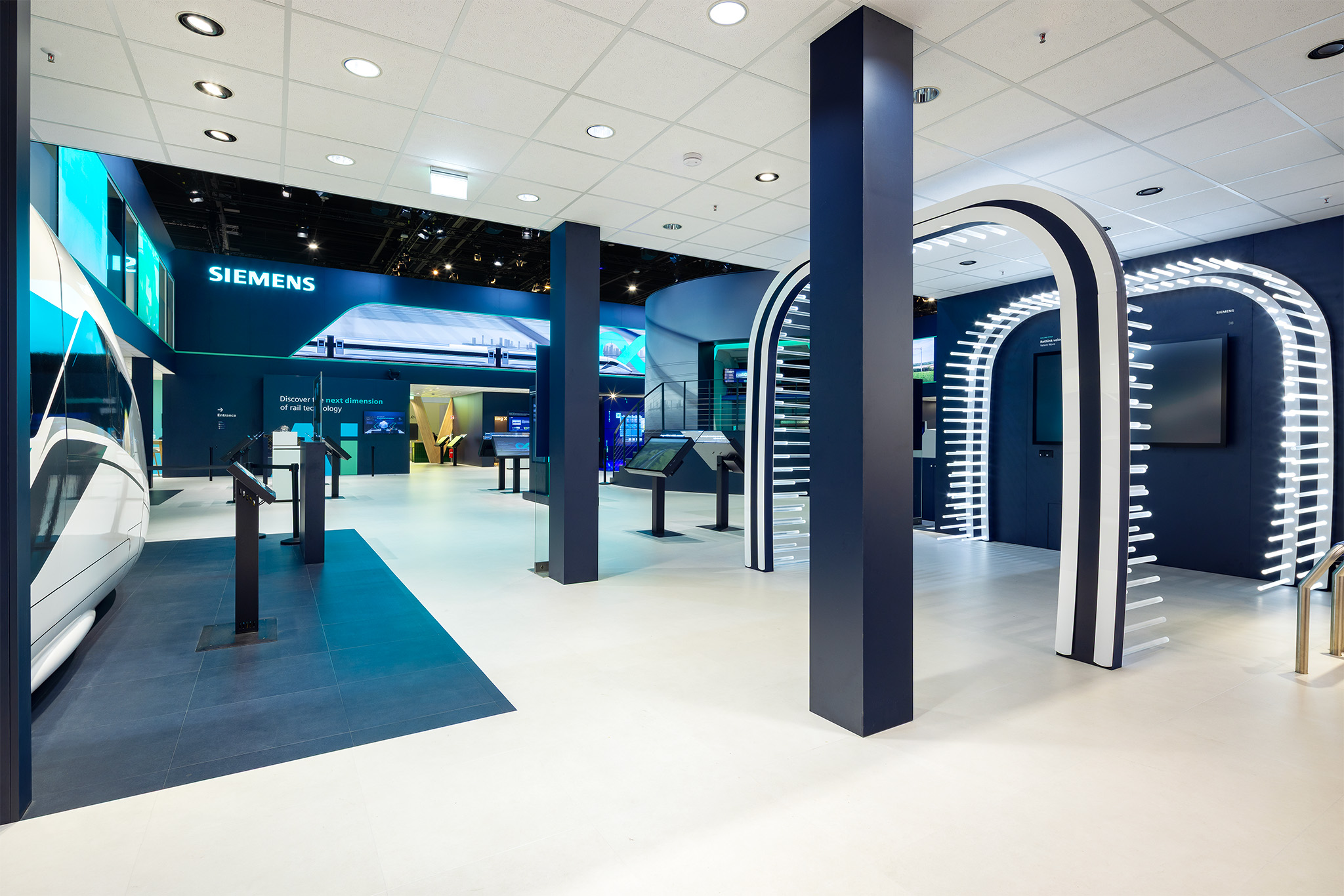 Beleuchtete Design-Bögen und Exponatbereich auf dem Siemens Messestand InnoTrans Berlin.