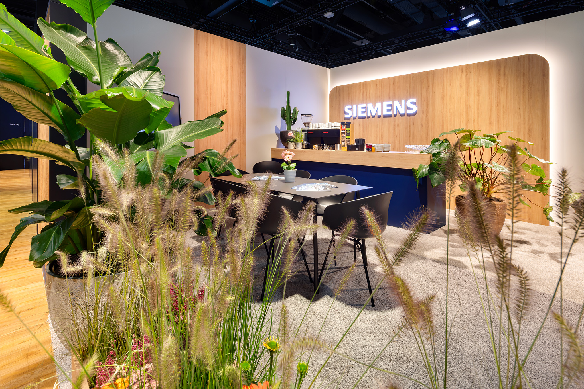 Gemütliche Bar-Lounge mit Pflanzen und Holzvertäfelung auf dem Siemens Messestand von Raumtechnik.