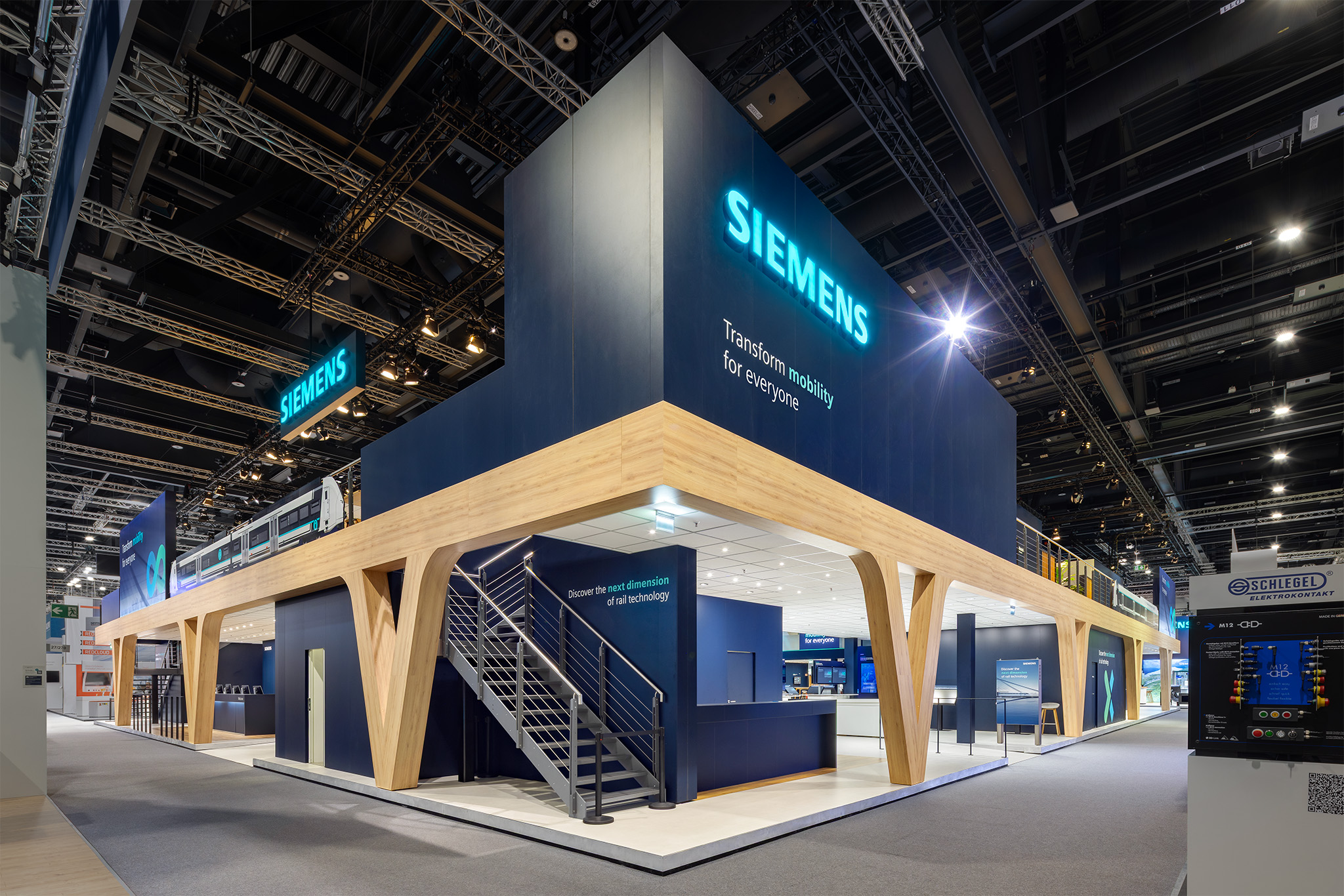 Außenansicht des zweistöckigen Siemens Messestands mit Holzstützen auf der InnoTrans 2026, gebaut von Raumtechnik.
