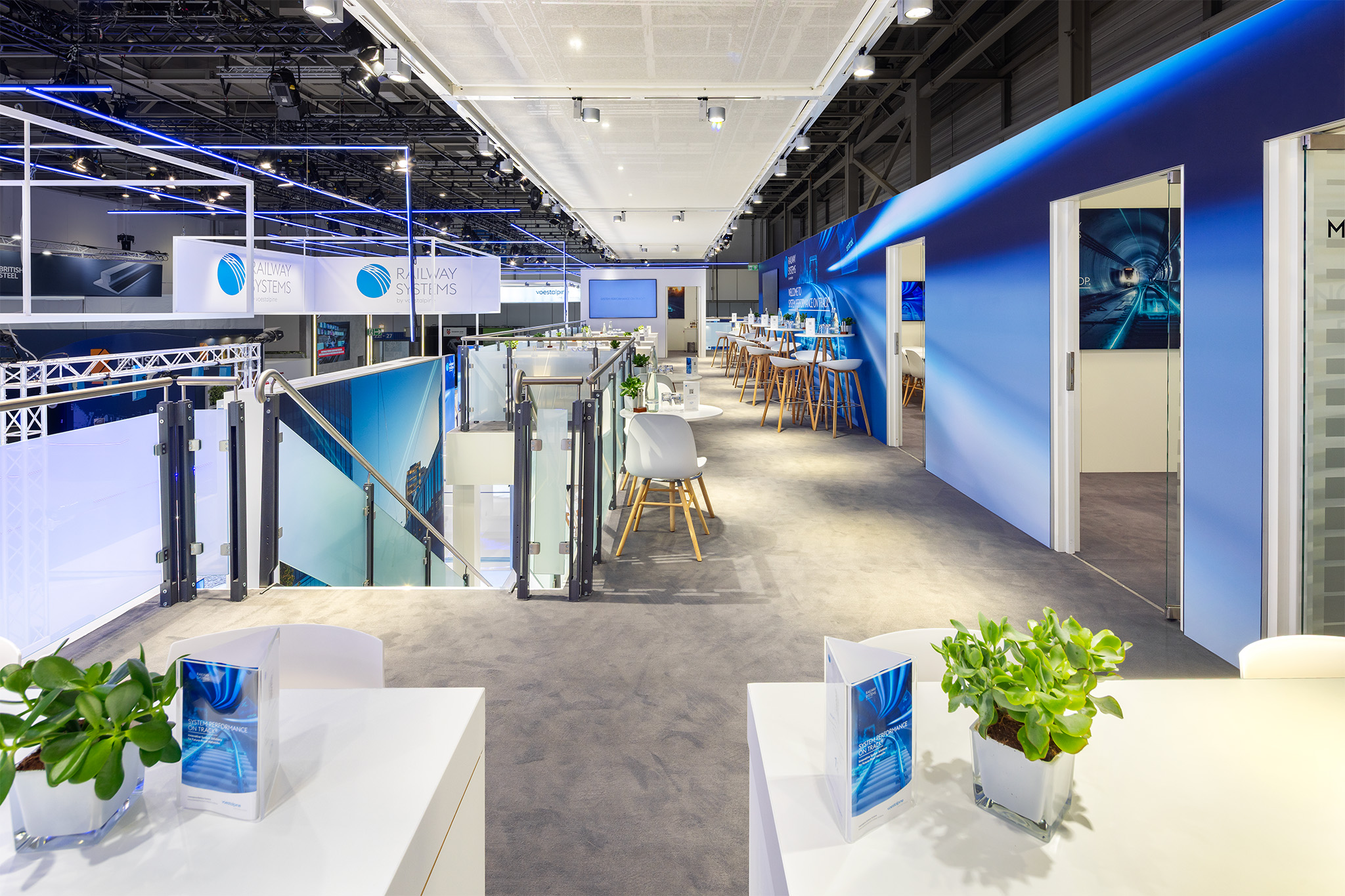 Moderner Doppelstock-Messestand von voestalpine Railway Systems auf der InnoTrans 2026 mit VIP-Lounge und Bar-Bereich, realisiert von Raumtechnik.